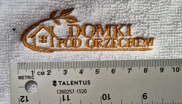 Złoty haft Domki Pod Orzechem na białej tkaninie frotte