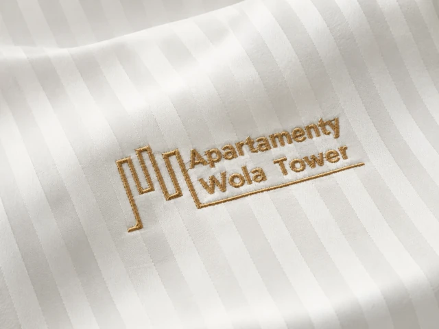 Złoty haft Apartamenty Wola Tower na białej tkaninie hotelowej