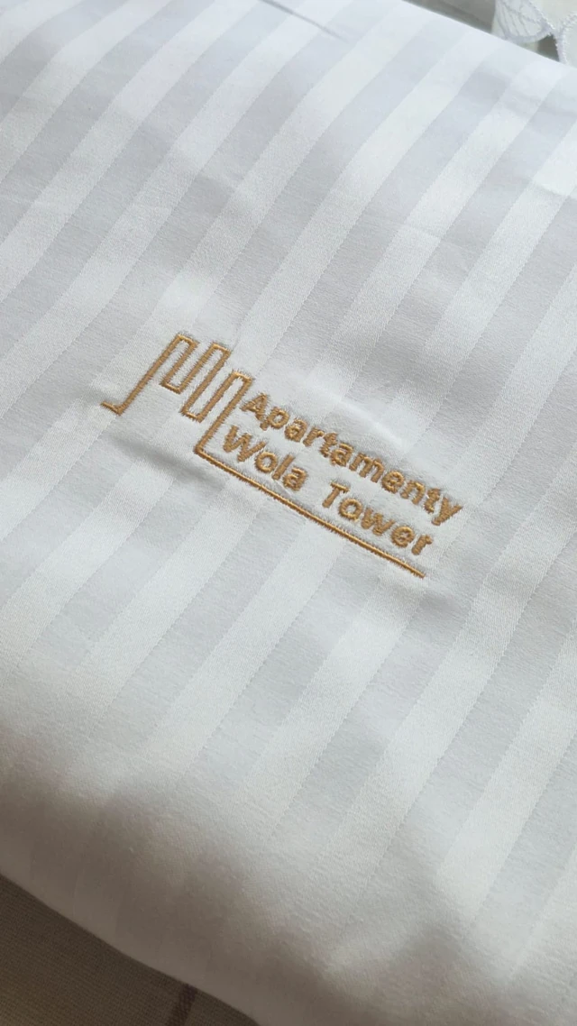 Haft Apartamenty Wola Tower na białej tkaninie w pasy